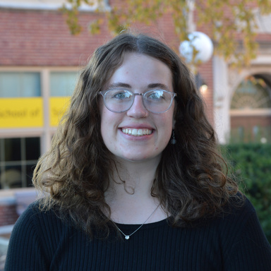 young woman, wavy brown shoulder-length hair, wearing glasses