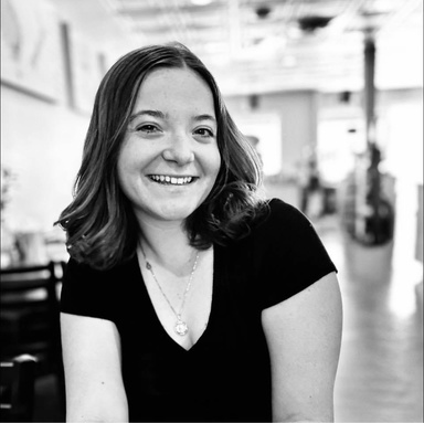 black and white photo of a woman sitting in a coffee shot facing the camera