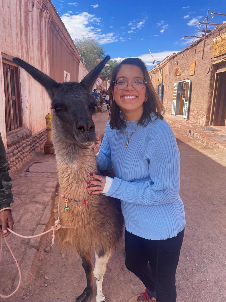 young woman with brown hair and glasses standing with llama