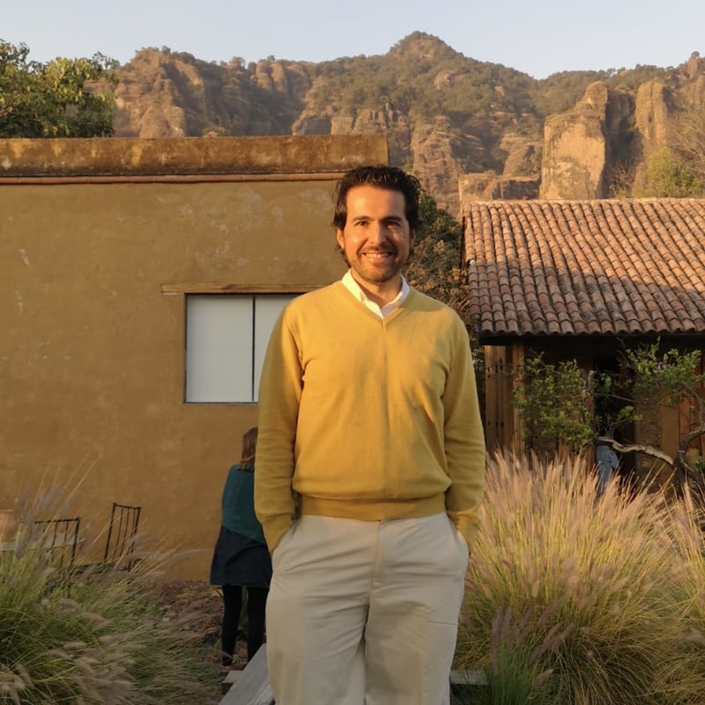 man in yellow sweater standing, smiling