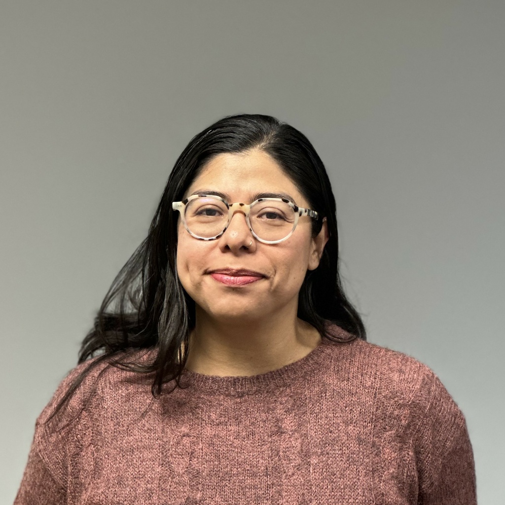 woman with long black hair and glasses against grey background