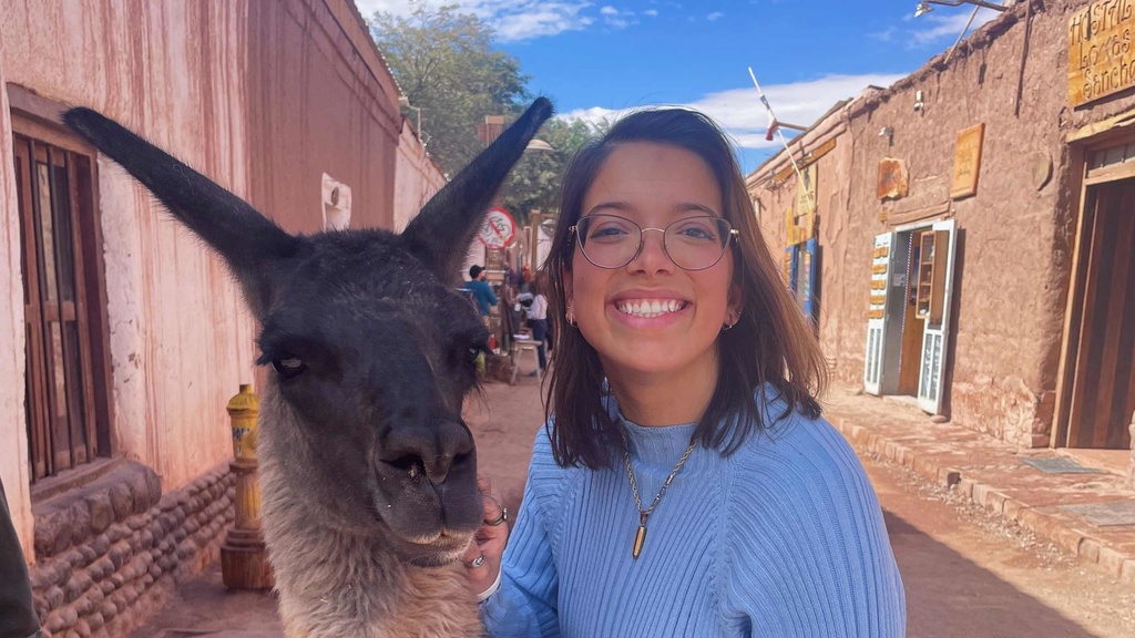 young woman with brown hair and glasses standing with llama