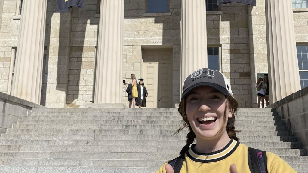 Sophie Perez standing in UIowa-themed clothing in front of the Old Capitol Building