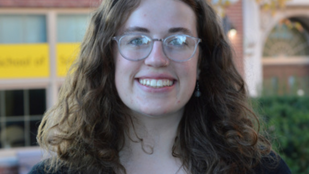 young woman, wavy brown shoulder-length hair, wearing glasses